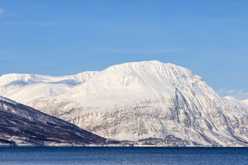 Snow-covered mountain and blue sea, winter landscape