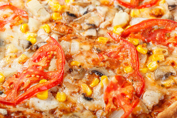 delicious pizza with chicken, mushrooms, cheese, tomatoes and corn on a wooden background