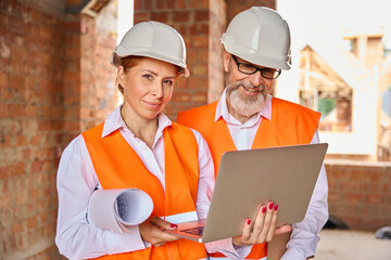 Construction professionals using portable computer in unfinished dwelling house