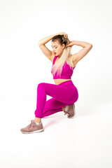 Woman in vibrant pink sports outfit kneeling with hands on hairs