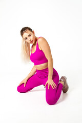 Woman in vibrant pink sports outfit both knees on floor and hands on upper legs