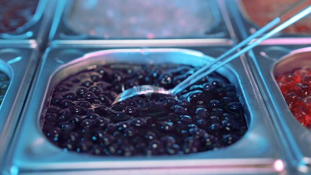 Close up shot of tasty, delicious, sweet boba tea bubbles stired by a metal spoon 