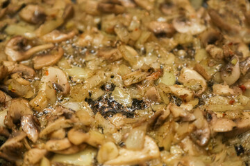 We cook mushrooms. Chopped mushrooms and golden onions in a frying pan close-up. Gastronomic background. Onions with mushrooms are fried in a frying pan. close-up, selective focus.