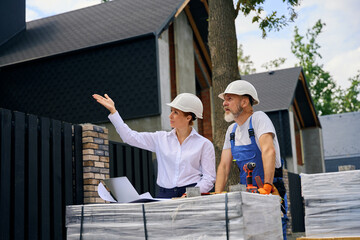 Professional specialist inspecting cottage facade in presence of housebuilder