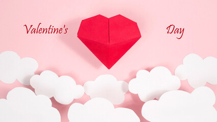 Greeting card "Happy Valentine's Day" with red paper volumetric origami heart. White clouds. Pale pink background.