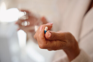 Obraz na płótnie Canvas Woman holds a painkiller pill in her hand
