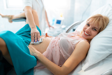 Beautiful smiling relaxed pregnant woman looking at camera while lying in bed before delivering...