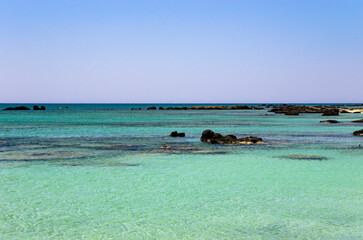 Landscape of a calm sea with dark stones in the water