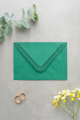 Wedding background, green invitation envelope on a gray background, top view
