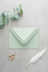 Wedding background, green invitation envelope on a gray background, top view - 702999039