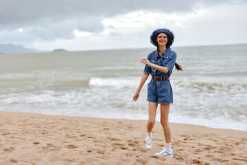 Sun-kissed Beauty enjoying Summer Vacation at the Tropical Beach: Young Woman with Casual Fashion and Elegant Hat, Relaxing by the White Sand, Admiring the Ocean and Blue Sky