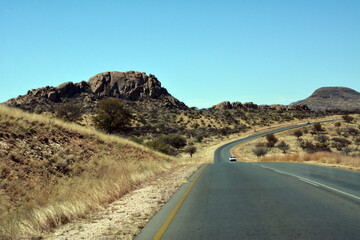 A deserted stony road in the hot desert foothills under a bright blue sky