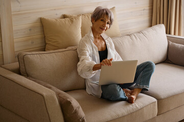 Pretty woman with a short haircut sits with a laptop
