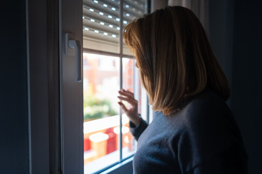 Woman with depression and sadness looking out the window at the outside.