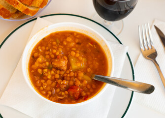 Lentil stew with chorizo, traditional Spanish dish, served on table in restaurant.