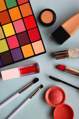 Various colorful make up products on bright blue background. Flat lay.