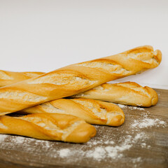 Barras de pan baguette sobre una mesa de madera con harina por encima 