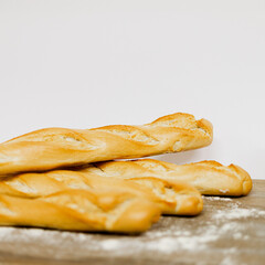 Barras de pan baguette sobre una mesa de madera con harina por encima 