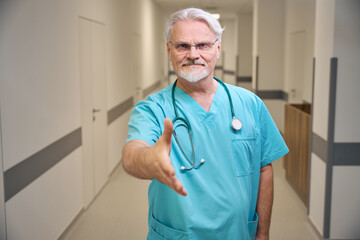 Serious doctor greeting patient in medical facility corridor