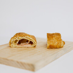 Napolitana de jamón y queso cortada. 
Napolitana de jamón y queso abierta por la mitad. Fotografía de producto de panadería. 