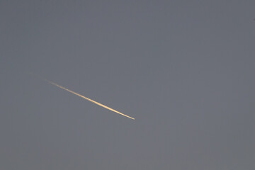 Jet stream from a airline during sunset, Image shows the vapour trail light up by the sun giving it...