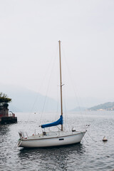 White sailing boat on lake Como. Water sports. The concept of a luxurious lifestyle, mountain background