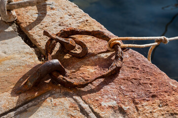 Old rusty metal mooring ring on an old stone pier, metal corrosion, passage of time