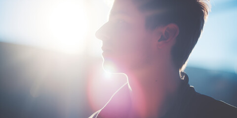 Young man in profile with sunlight creating a silhouette, a sense of contemplation in his pose