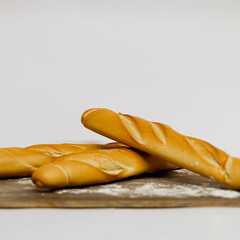 Barras de pan baguette sobre mesa de madera con harina y fondo blanco 