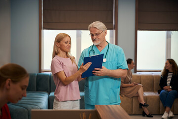 Obraz premium Clinician showing medical document to out-patient in hospital foyer