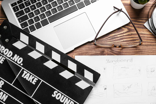 Storyboard with movie clapper, laptop and eyeglasses on wooden background