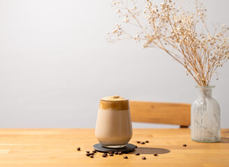 Dalgona coffee. Whipped instant coffee in a glass with beans on a wooden background with dry...