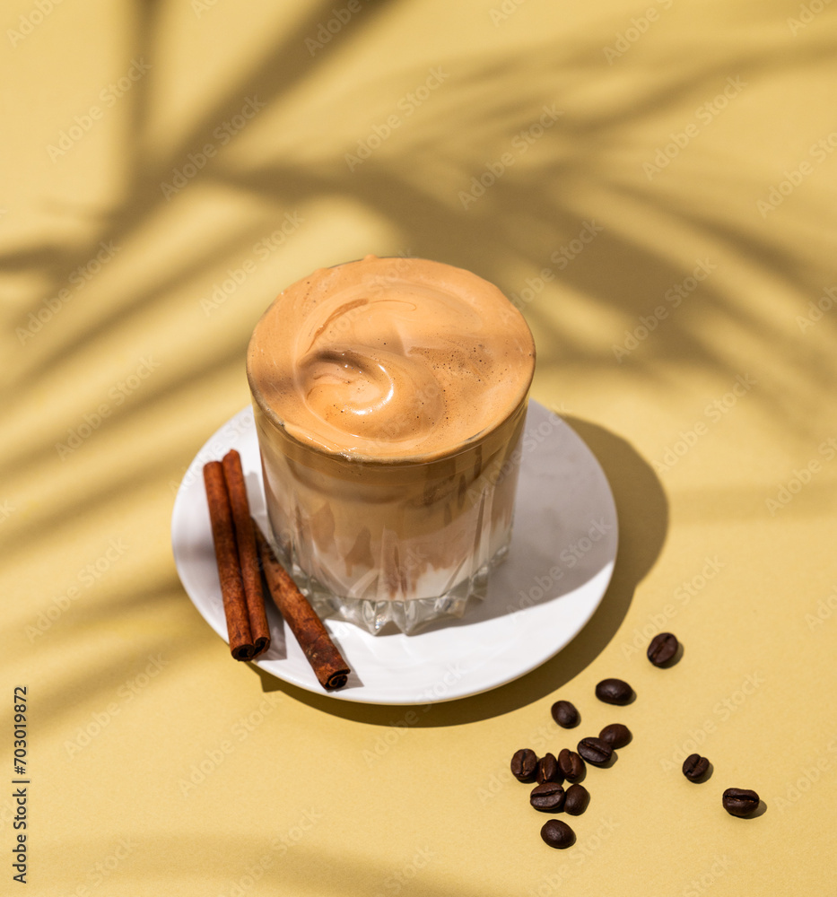 Wall mural Dalgona coffee. Whipped instant coffee in a glass on a saucer with cinnamon sticks