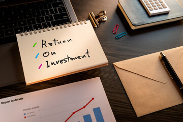 There is notebook with the word Return On Investment. It is as an eye-catching image.