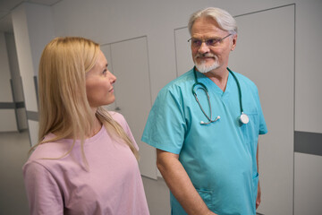 Clinician talking to female patient in clinic corridor
