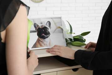 Women with picture of dog and flowers in room, closeup. Pet funeral