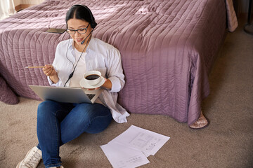 Obraz premium Cheerful freelancer using laptop during coffee break in hotel room