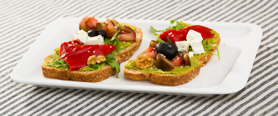 Sandwich with avocado, feta cheese, vegetables and walnut at plate..