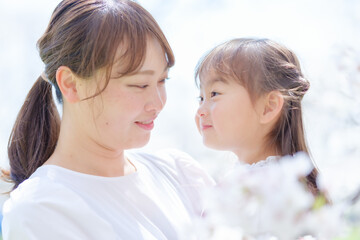 桜の前で見つめ合う女の子とお母さん