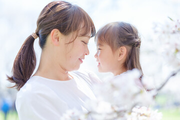 桜の前で見つめ合う女の子とお母さん