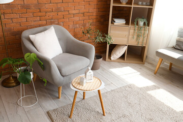 Stylish grey armchair and coffee table in interior of living room