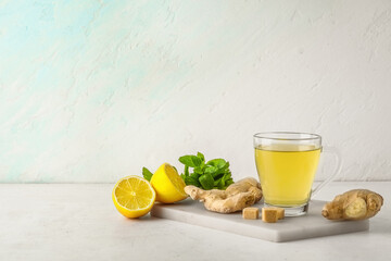 Glass cup of ginger tea with lemon and mint on white background
