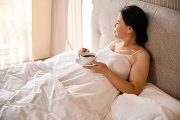 Obraz na płótnie Canvas Female is having her morning coffee in bedroom upon awakening