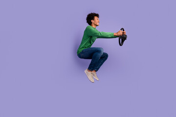 Fototapeta na wymiar Full length photo of cheerful funny guy wear green pullover riding car jumping empty space isolated purple color background