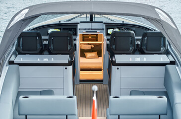 Close-up view of a relaxation area on the open teak deck of an expensive motorboat at sunny day, Monaco yacht show, large boat exhibition, wealth life, table and chairs