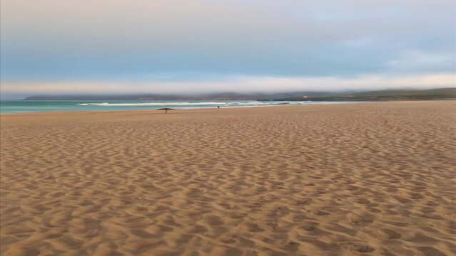 Sandy seashore gloomy day vertically. Lonely people walking coast with waves