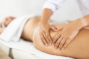 Fototapeta na wymiar Female masseuse doing thigh massage closeup to young woman client
