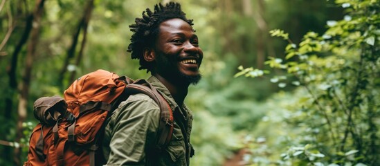 A joyful African-American man with a backpack, glancing sideways, hiking in the woods with his girlfriend.