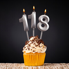 Birthday candle number 118 - Anniversary cupcake on black background
