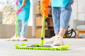 Female janitor mopping floor in room, closeup